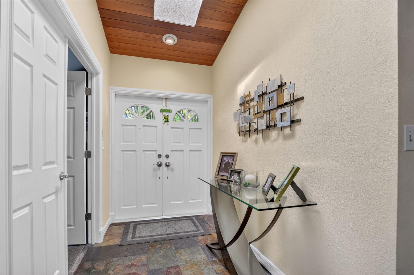 An entryway features a wood-paneled ceiling, slate tile flooring, a glass console table, and double doors — 22718 Vistawood Way, Boca Raton FL 33428, BOCA RATON, FL