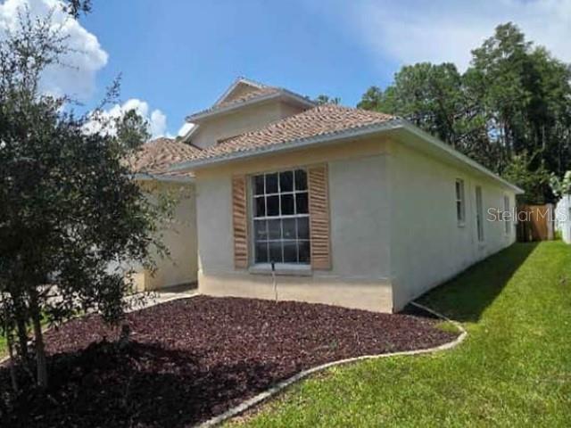 A single-story house with beige stucco walls, a shingled roof, and a landscaped front yard — 12533 SPARKLEBERRY ROAD, TAMPA, FL