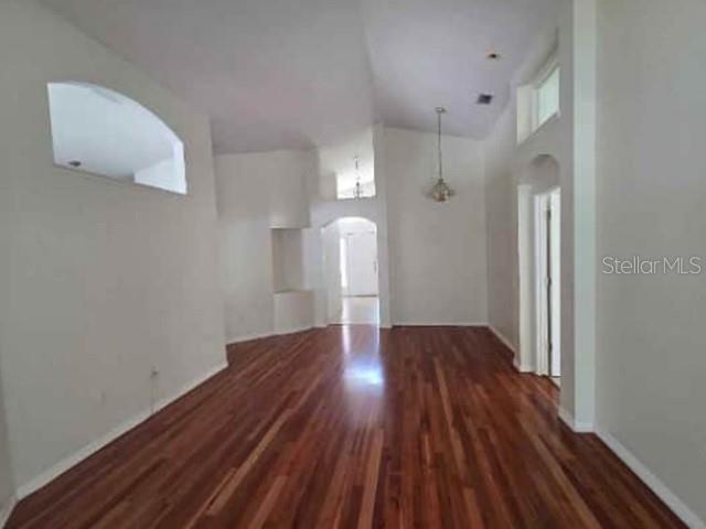 An empty room with high ceilings, light-colored walls, and polished hardwood flooring — 12533 SPARKLEBERRY ROAD, TAMPA, FL