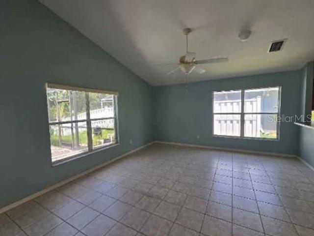 An empty room with light blue walls, tile flooring, a ceiling fan, and two windows — 12533 SPARKLEBERRY ROAD, TAMPA, FL