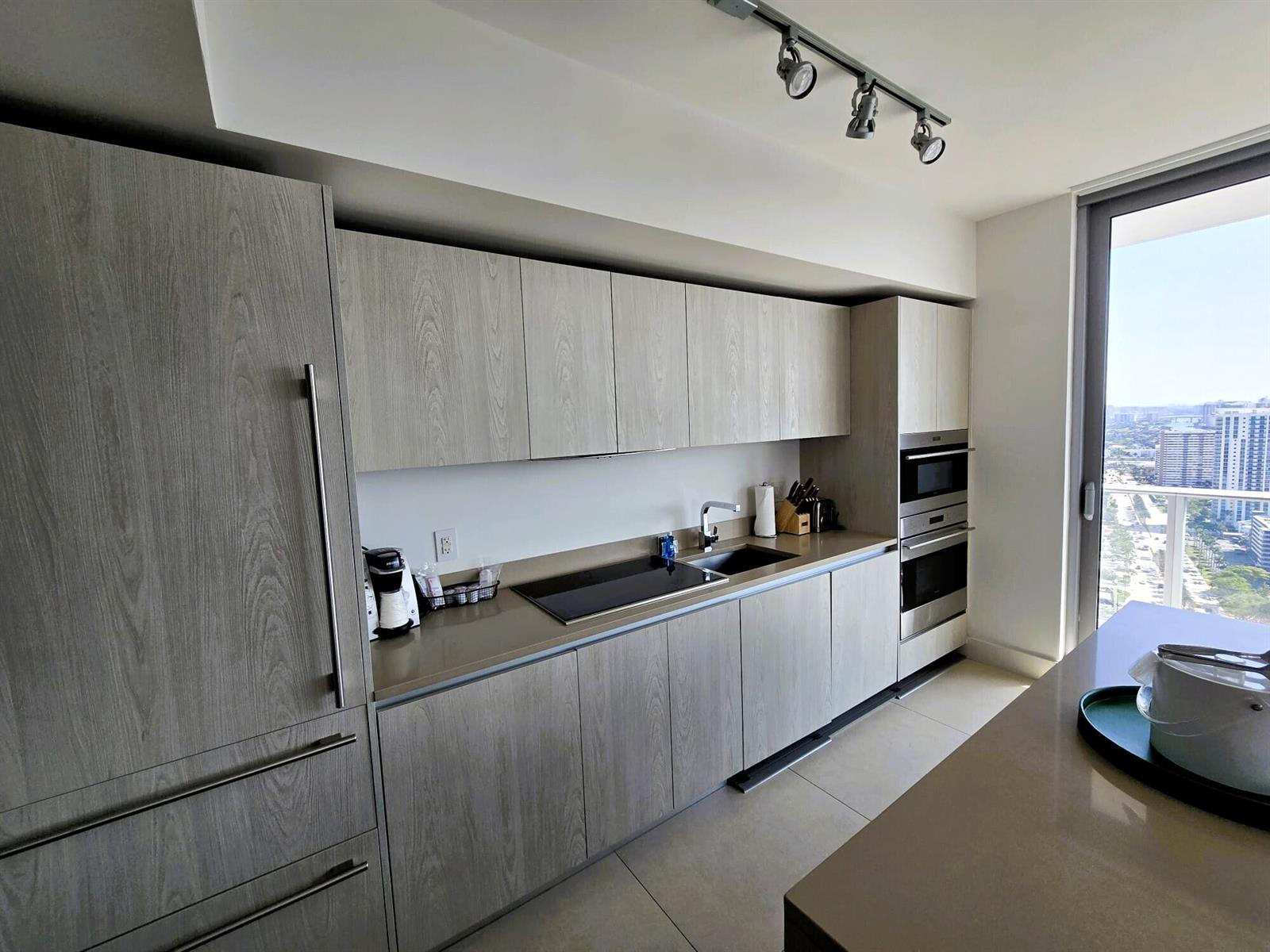 A modern kitchen features light wood-grain cabinetry, stainless steel appliances, and a view of city buildings — 4111 S Ocean Drive # 3011, Hollywood FL 33019, HOLLYWOOD, FL