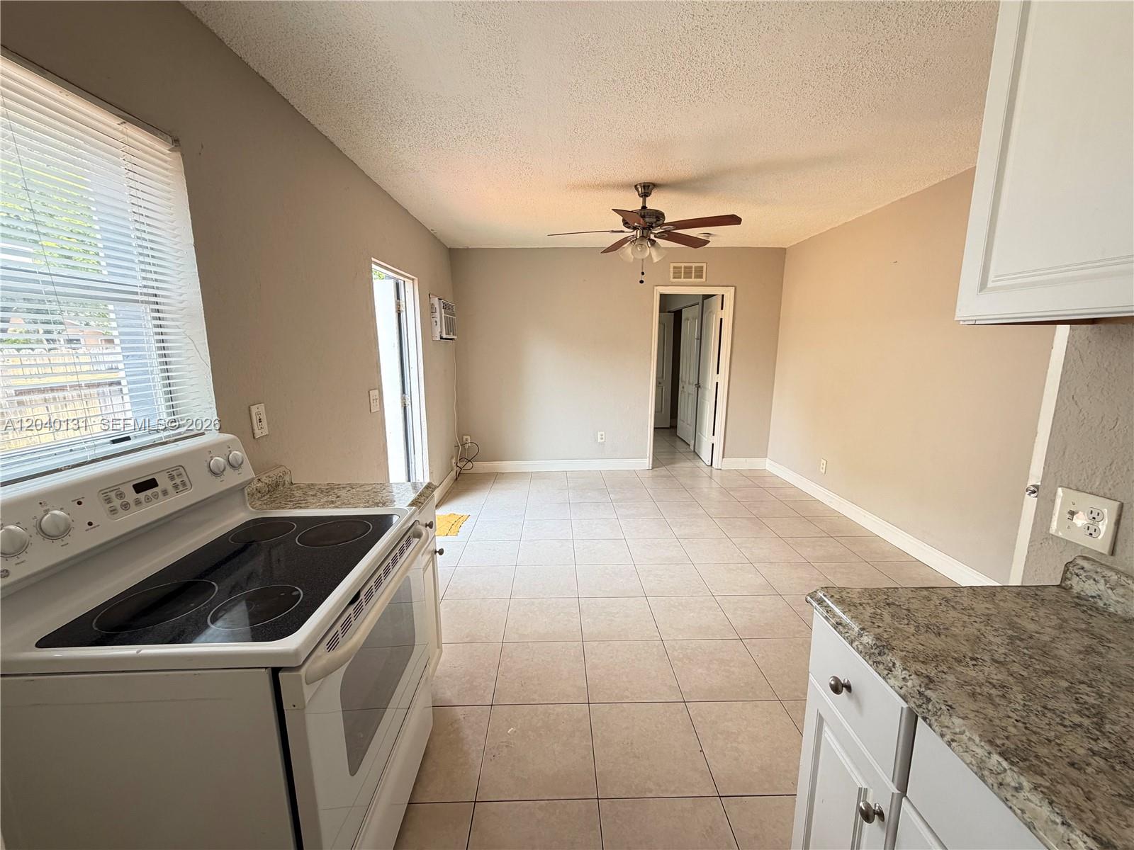 A kitchen with tile flooring, a white electric stove, and granite countertops leads to an open area — 6012 SW 38th St # 4, Miramar FL 33023, MIRAMAR, FL