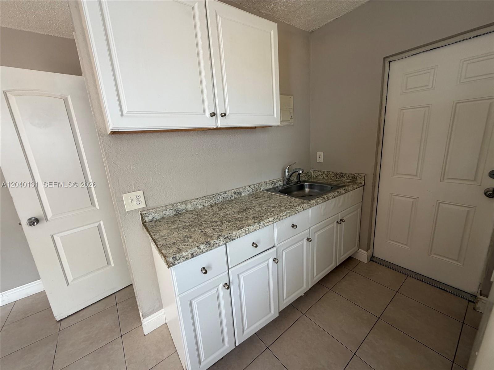 A small kitchen area features white cabinets, granite countertops, a sink, and tile flooring — 6012 SW 38th St # 4, Miramar FL 33023, MIRAMAR, FL