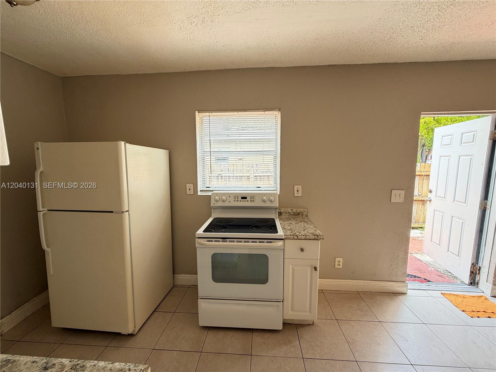 A kitchen features a white refrigerator, electric stove, single cabinet, and tile flooring — 6012 SW 38th St # 4, Miramar FL 33023, MIRAMAR, FL