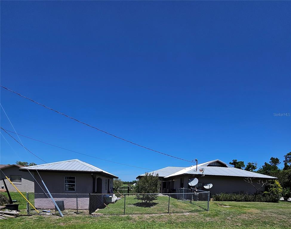 A detached garage and a house sit in a grassy yard enclosed by a fence — 3481 NE MASTERS AVENUE, ARCADIA, FL