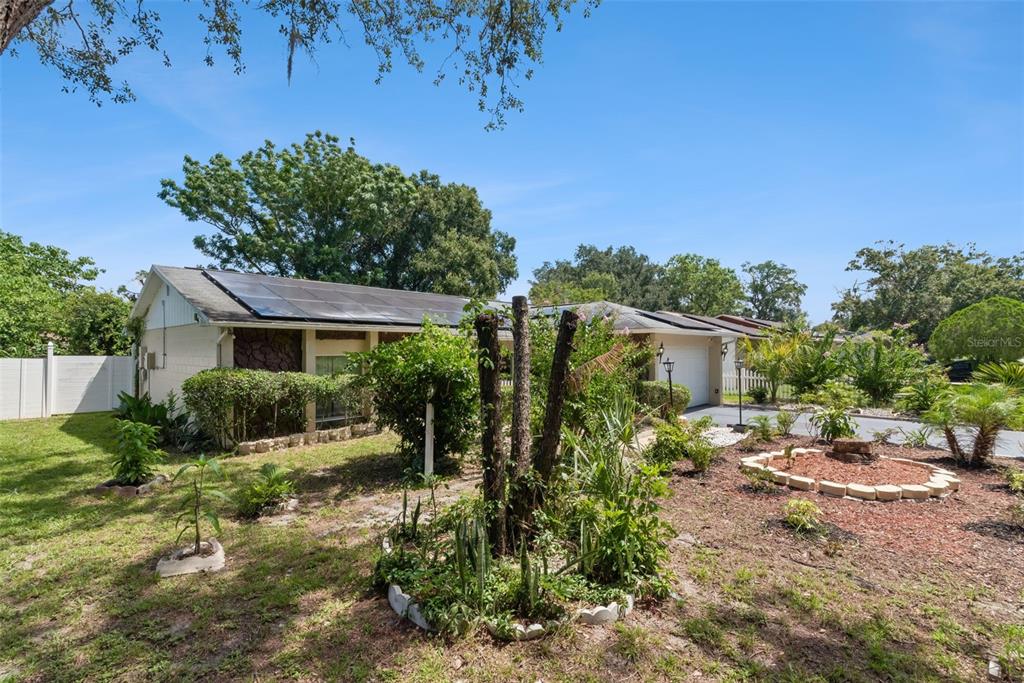 A single-story house with solar panels on the roof and a landscaped front yard — 5851 HUTTON DRIVE, ORLANDO, FL