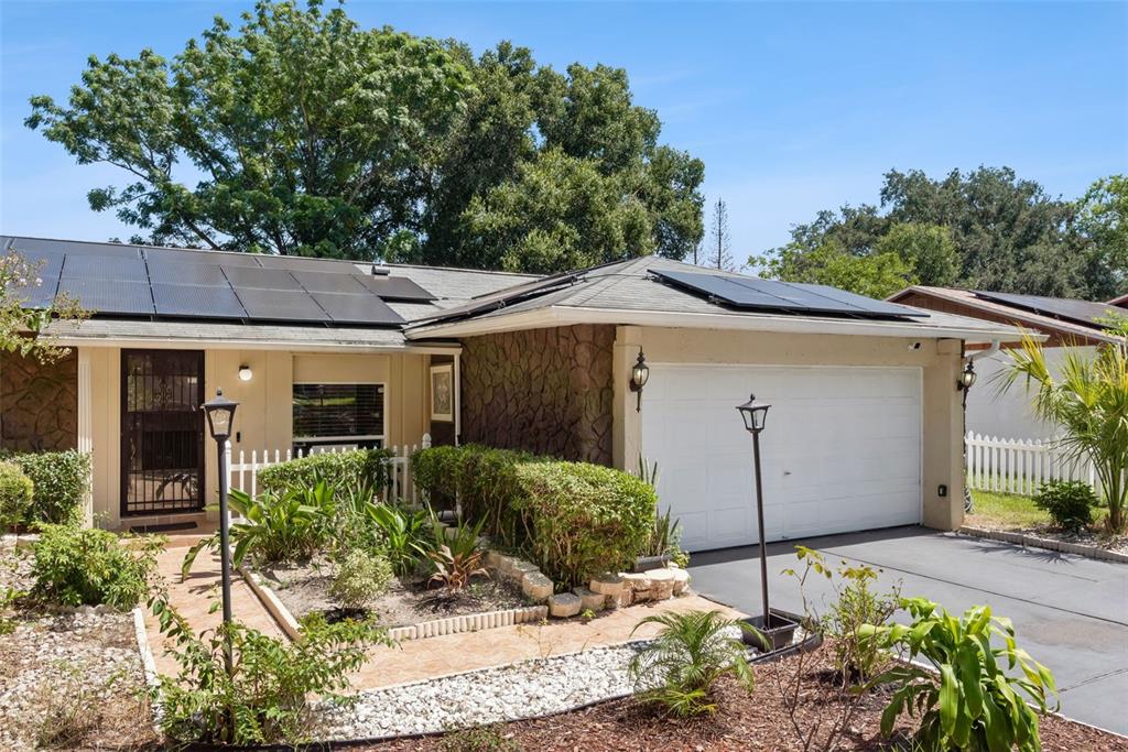 A single-story house features a white garage, stone facade, and solar panels on the roof — 5851 HUTTON DRIVE, ORLANDO, FL