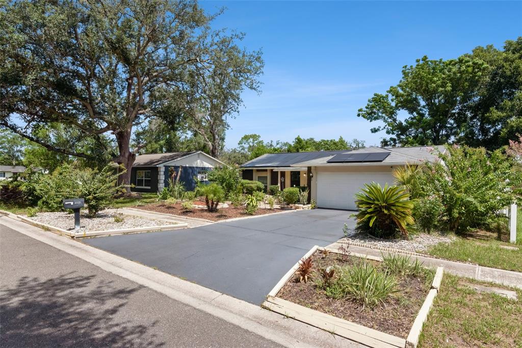 A single-story house with a paved driveway, solar panels on the roof, and landscaped yard — 5851 HUTTON DRIVE, ORLANDO, FL