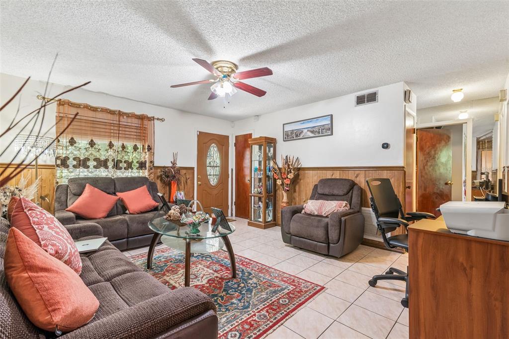 A living room with tile floors, wood wainscoting, a ceiling fan, and brown upholstered furniture — 5851 HUTTON DRIVE, ORLANDO, FL