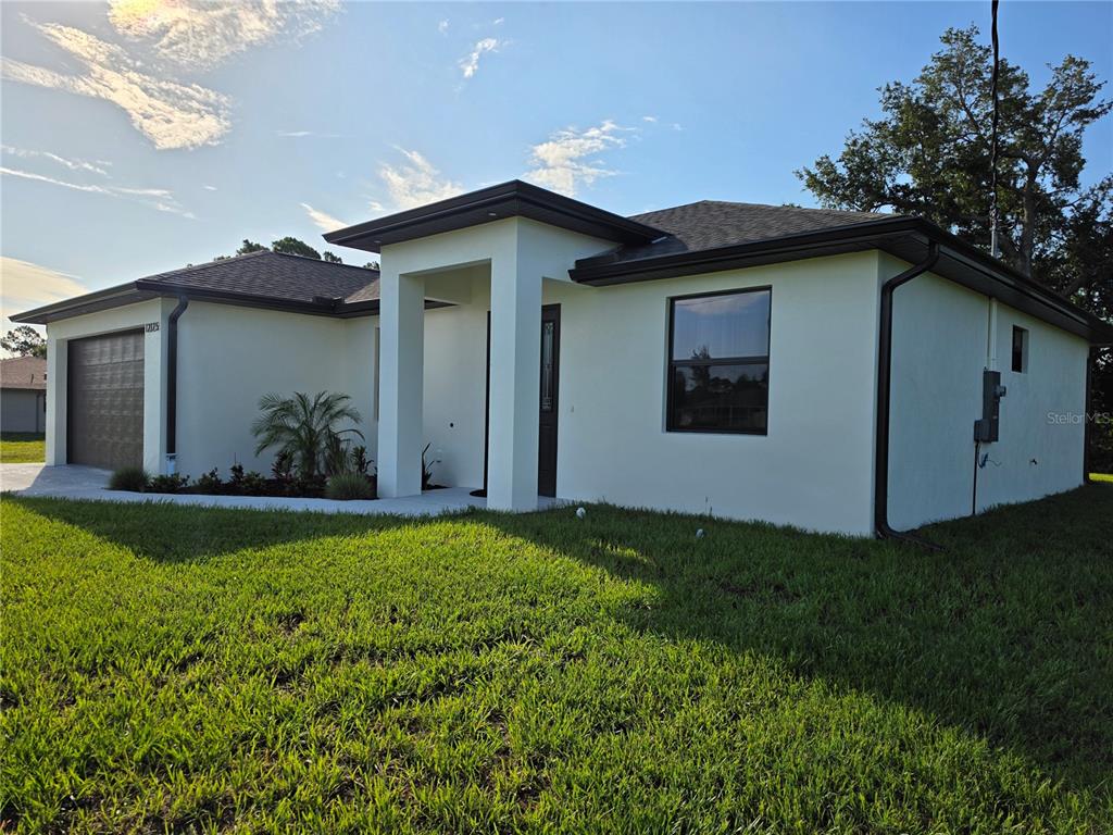 A modern, single-story house with white stucco walls, a dark roof, and a front garage — 12125 MADRID AVENUE, NORTH PORT, FL