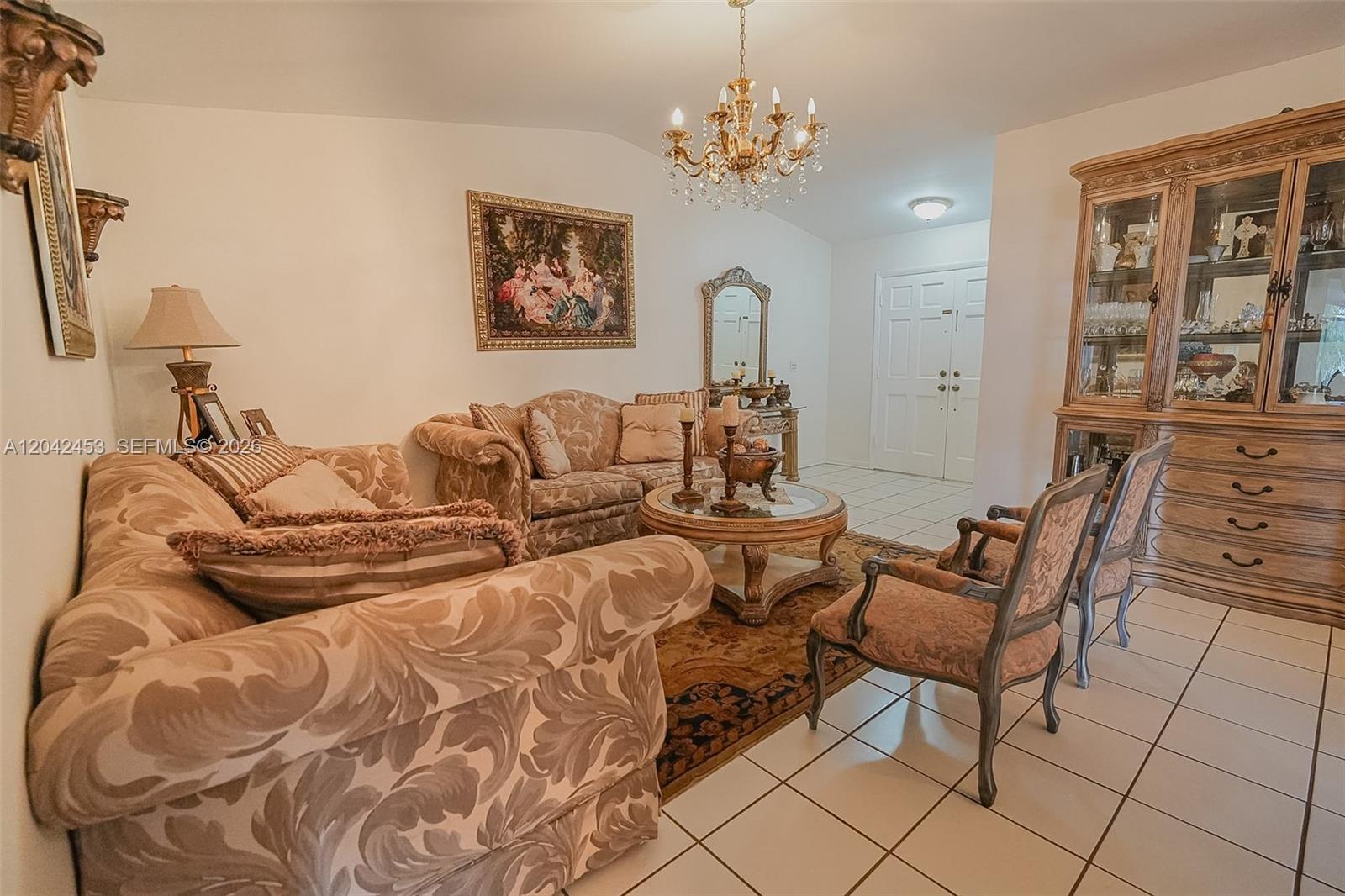 A formal living room features patterned furniture, a crystal chandelier, and a large wooden hutch — 10920 SW 143rd Ct, Miami FL 33186, MIAMI, FL