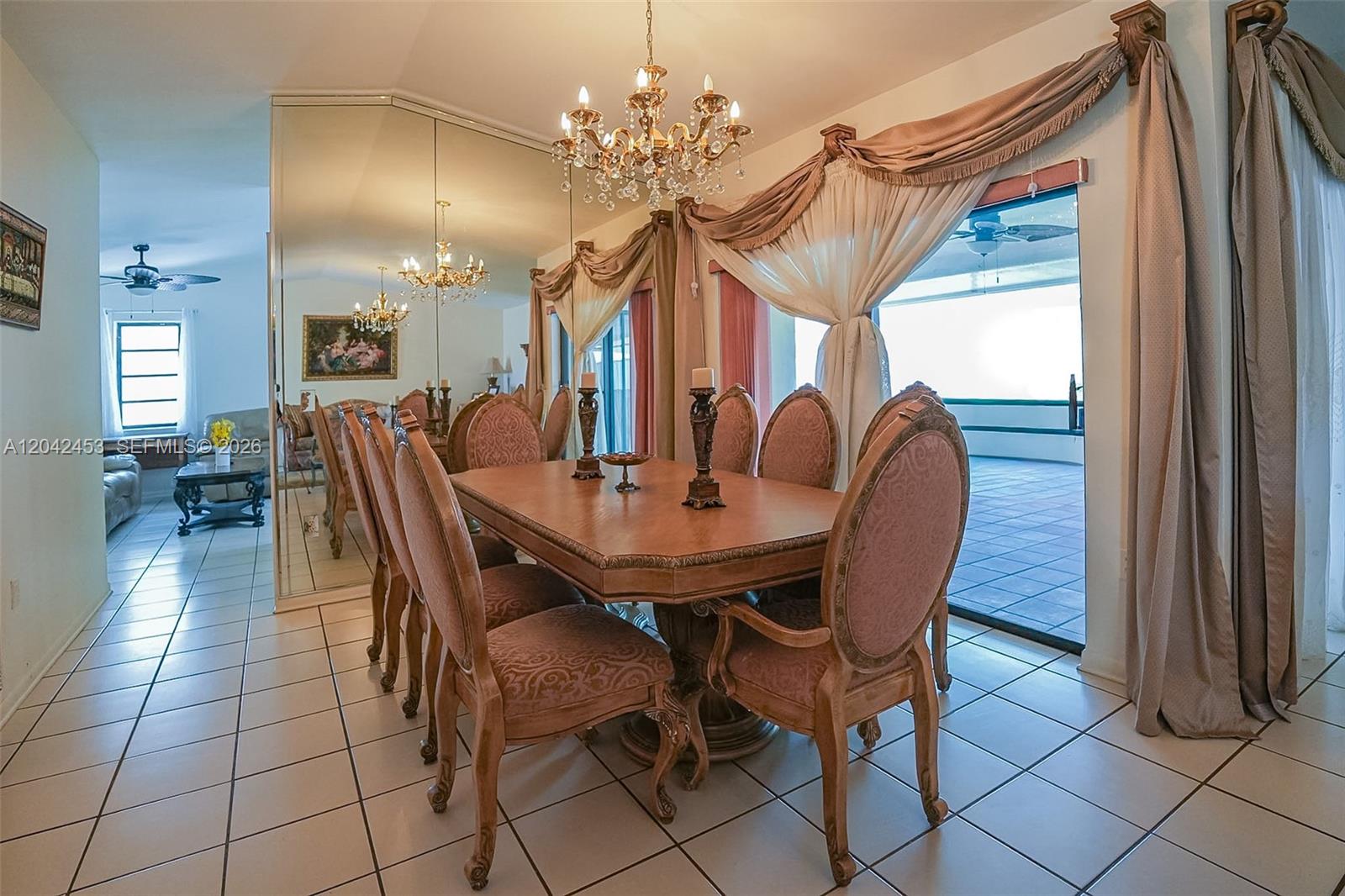 A dining room features a wooden table, upholstered chairs, a crystal chandelier, and mirrored walls — 10920 SW 143rd Ct, Miami FL 33186, MIAMI, FL