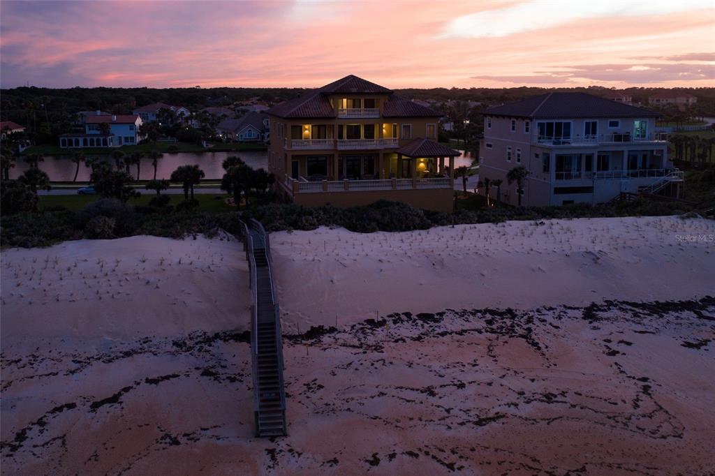 An aerial view shows two large houses behind a sandy beach with a wooden staircase — 35 CALLE DEL SUR, PALM COAST, FL