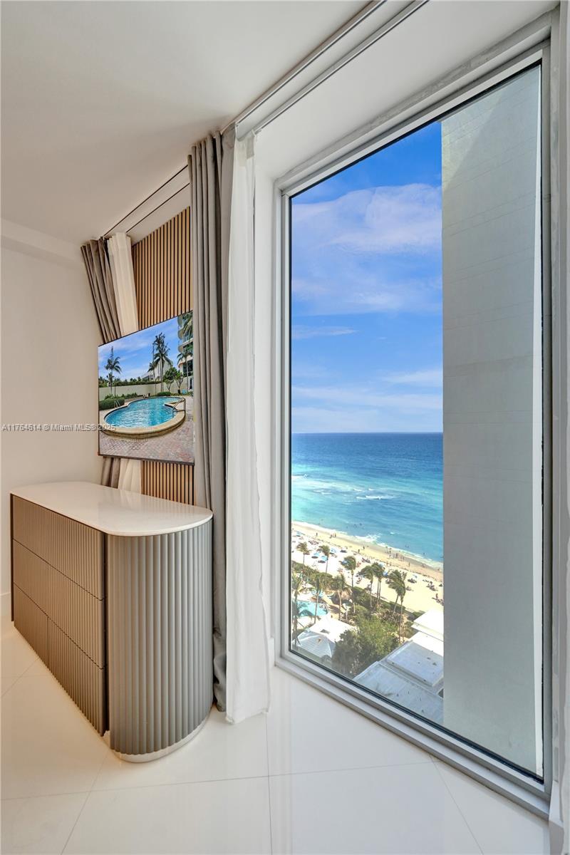 A bedroom features a curved dresser, a wall-mounted television, and a floor-to-ceiling ocean view — 4001 S Ocean Dr # 16P, Hollywood FL 33019, HOLLYWOOD, FL
