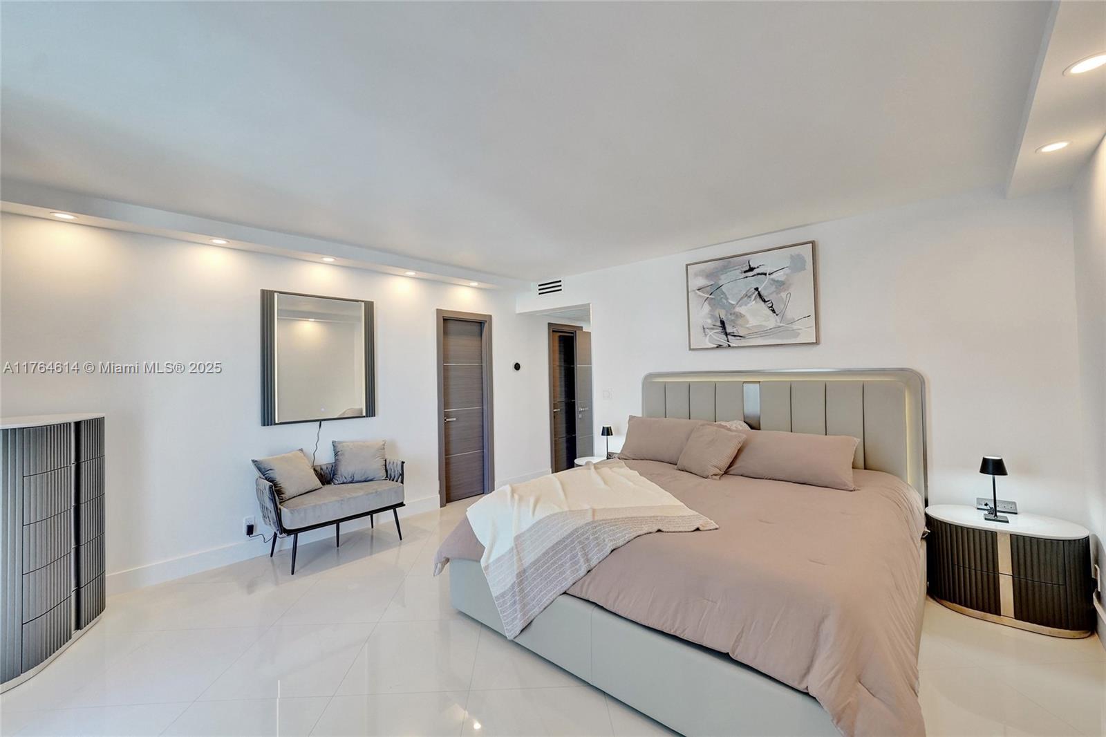 A modern bedroom features a large bed, a small bench, and neutral-toned furniture — 4001 S Ocean Dr # 16P, Hollywood FL 33019, HOLLYWOOD, FL