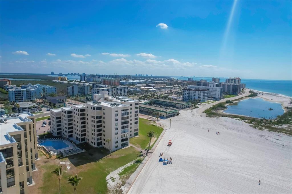An aerial view shows beachfront apartment buildings next to a wide sandy beach and ocean — 6670 ESTERO BOULEVARD UNIT A104, FORT MYERS BEACH, FL