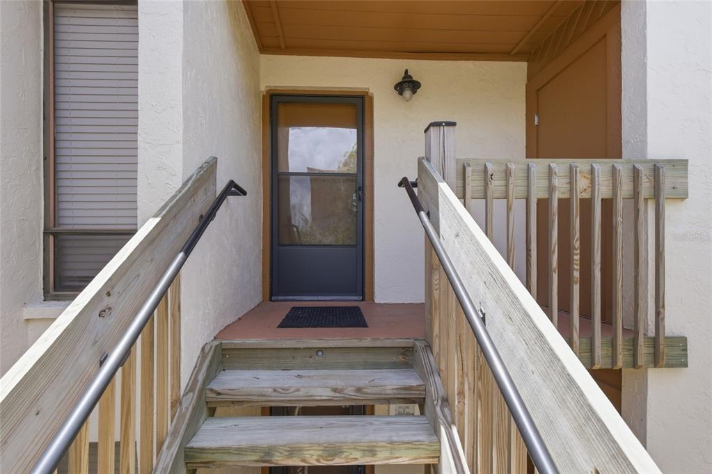 A wooden staircase with metal handrails leads to a front door with a screen — 1500 COVE II PLACE UNIT 531, SARASOTA, FL