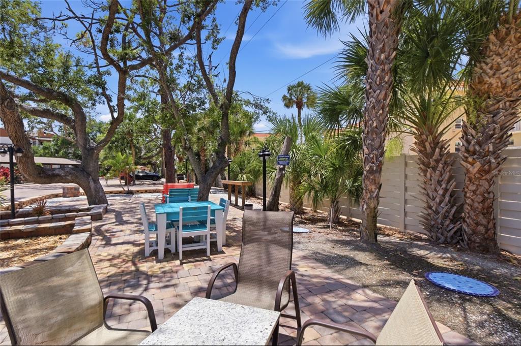 A paved outdoor patio features a blue table, chairs, and palm trees under a sunny sky — 1500 COVE II PLACE UNIT 531, SARASOTA, FL