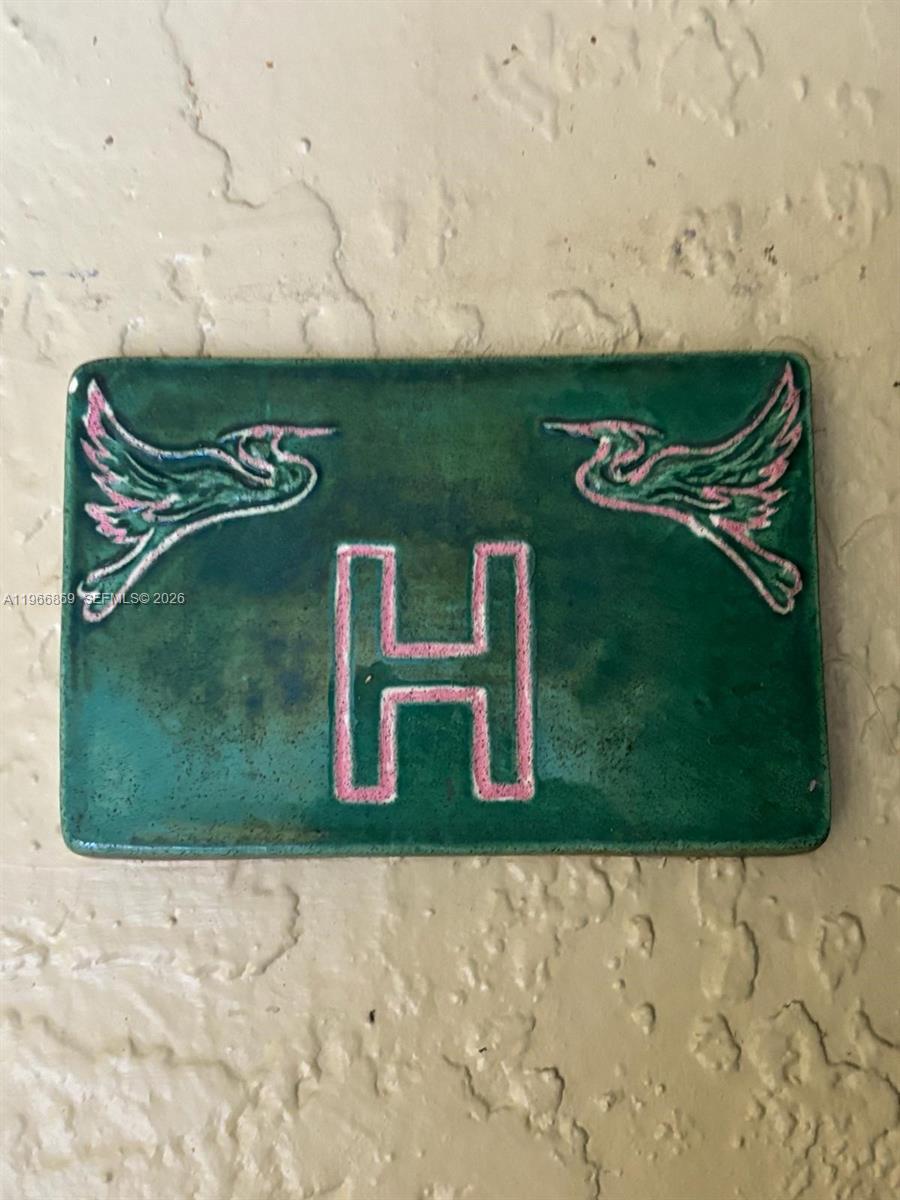 A rectangular green ceramic plaque features a pink letter H flanked by two birds — 18328 NW 68th Ave # H, Hialeah FL 33015, HIALEAH, FL