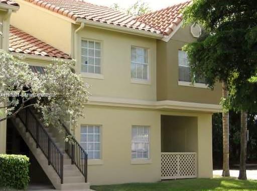 A two-story tan building features a tiled roof, an exterior staircase, and a lattice-enclosed patio — 18328 NW 68th Ave # H, Hialeah FL 33015, HIALEAH, FL
