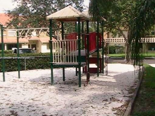 A playground with a climbing structure and monkey bars sits on a sandy surface outdoors — 18328 NW 68th Ave # H, Hialeah FL 33015, HIALEAH, FL