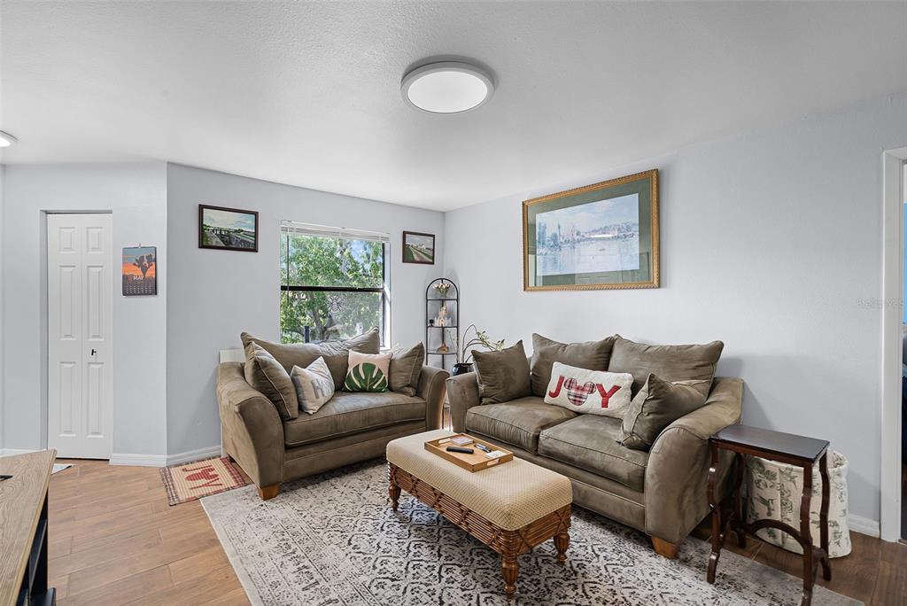 A living room features two brown sofas, a patterned area rug, and a central ottoman — 3028 PARKWAY BOULEVARD UNIT 308, KISSIMMEE, FL