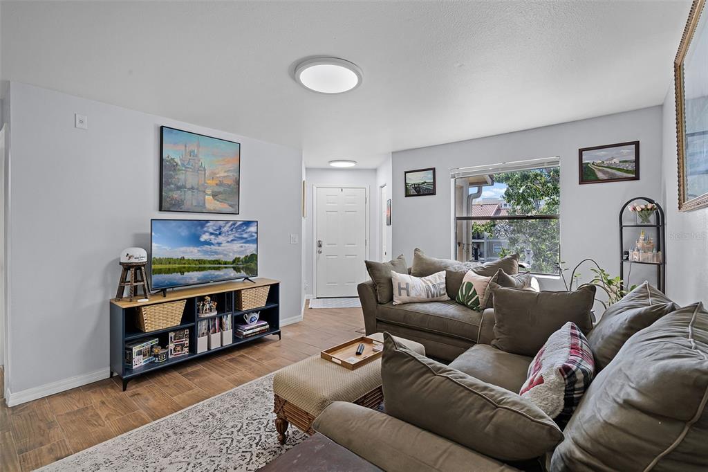 A living room features a television on a media console, a sofa, and a window — 3028 PARKWAY BOULEVARD UNIT 308, KISSIMMEE, FL