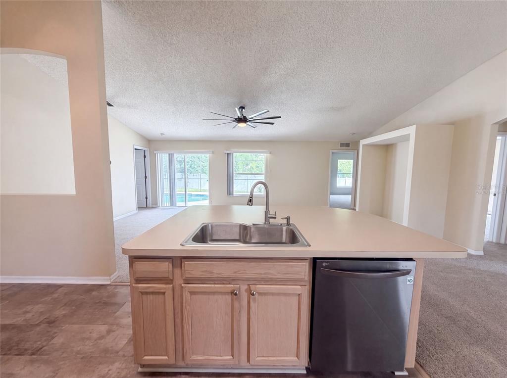 A kitchen island with a stainless steel sink and dishwasher faces a living area — 2366 BELEN DRIVE, DELTONA, FL