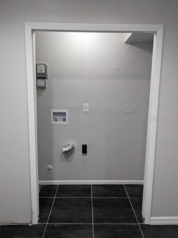 A laundry closet with a washer hookup, dryer vent, and black tile flooring — 165 WINDTREE LANE UNIT U, WINTER GARDEN, FL