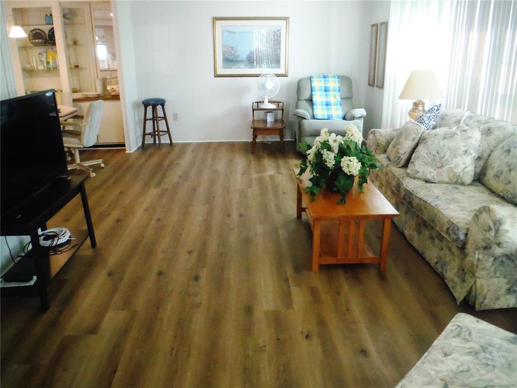 A living room features wood-look flooring, a floral sofa, a coffee table, and a recliner — 141 FOREST LANE UNIT 13, SAFETY HARBOR, FL