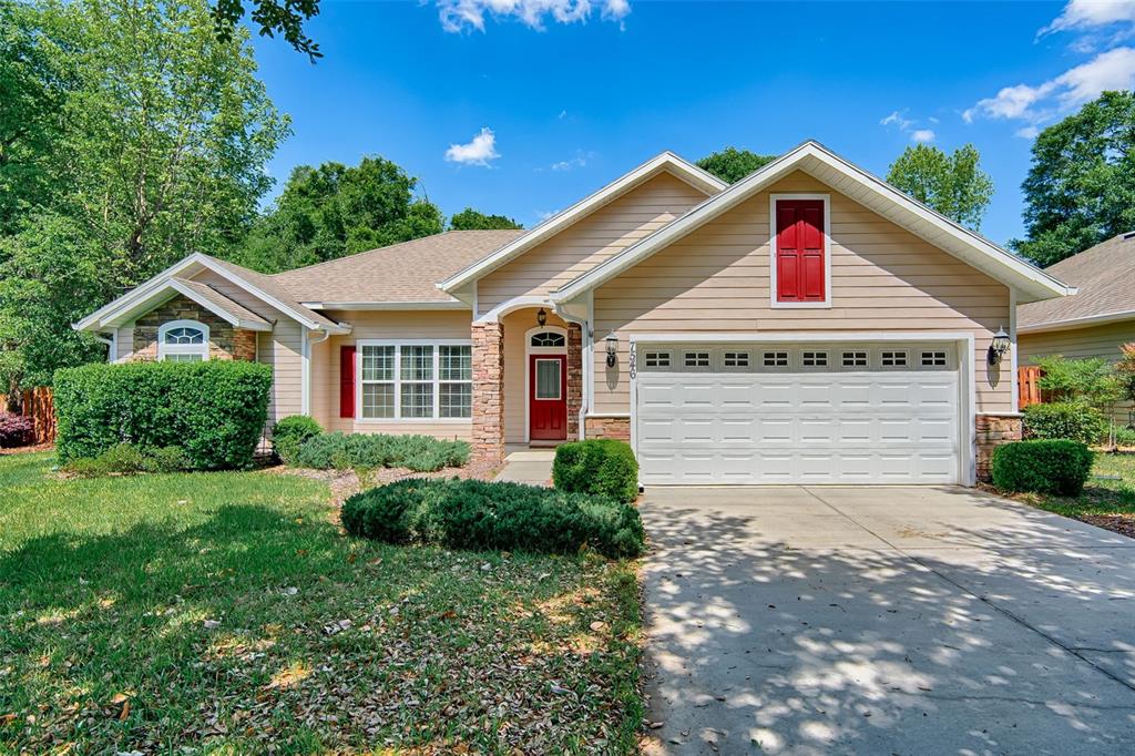 A single-story house with beige siding, a red front door, and a two-car garage — 7546 SW 90 DRIVE, GAINESVILLE, FL