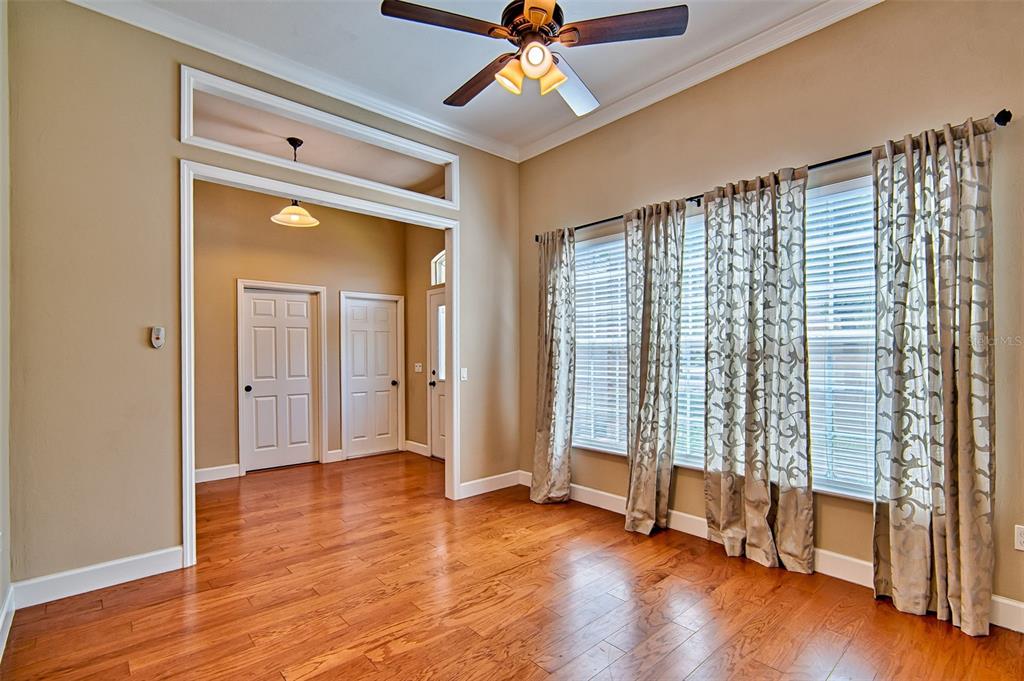 A room with hardwood floors, a ceiling fan, and large windows covered by patterned curtains — 7546 SW 90 DRIVE, GAINESVILLE, FL