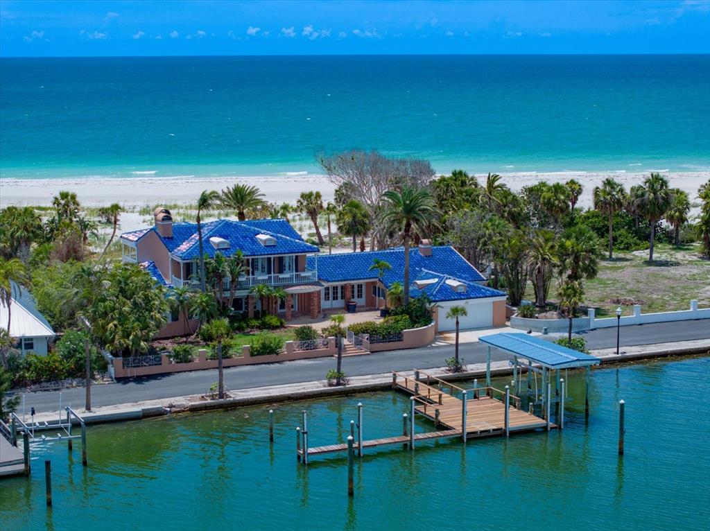 An aerial view of a coastal house with a blue tile roof, dock, and beach — 1114 MANDALAY POINT, CLEARWATER BEACH, FL