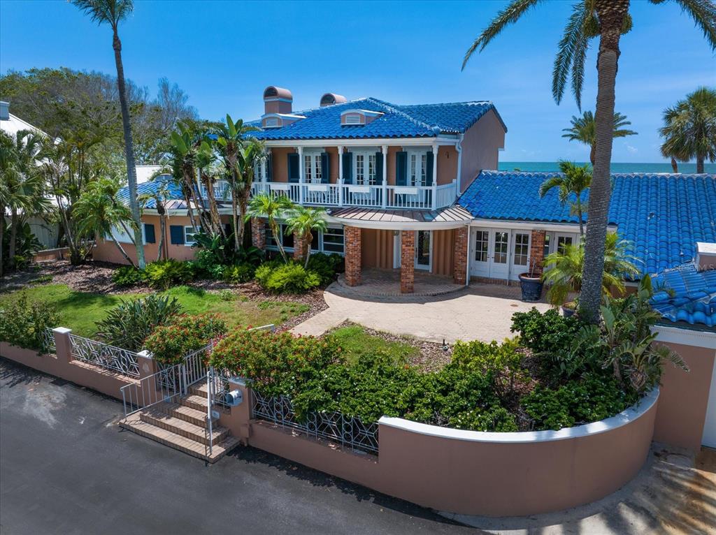 A two-story house with a blue tile roof, white balcony, and a gated front courtyard — 1114 MANDALAY POINT, CLEARWATER BEACH, FL