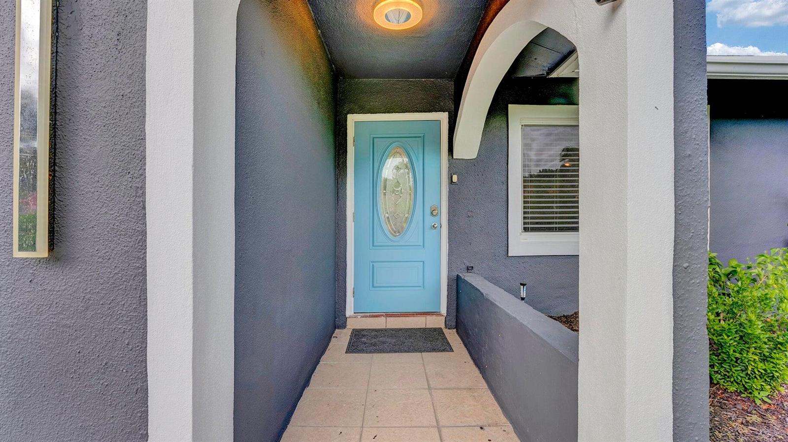A light blue front door is set within a covered entryway with gray stucco walls — 2941 Angler Drive, Delray Beach FL 33445, DELRAY BEACH, FL