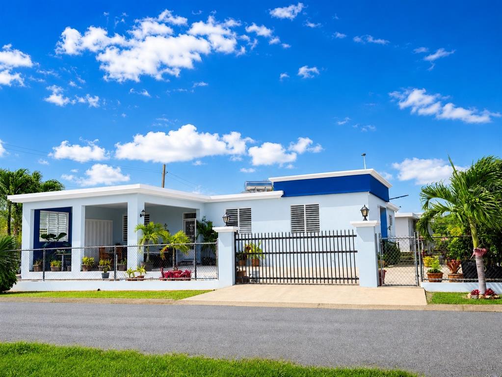 A light blue single-story house features a gated driveway, a covered porch, and palm trees — 467 BARRIO CAMASEYES, AGUADILLA, KM 4.8 INT, AGUADILLA, PR