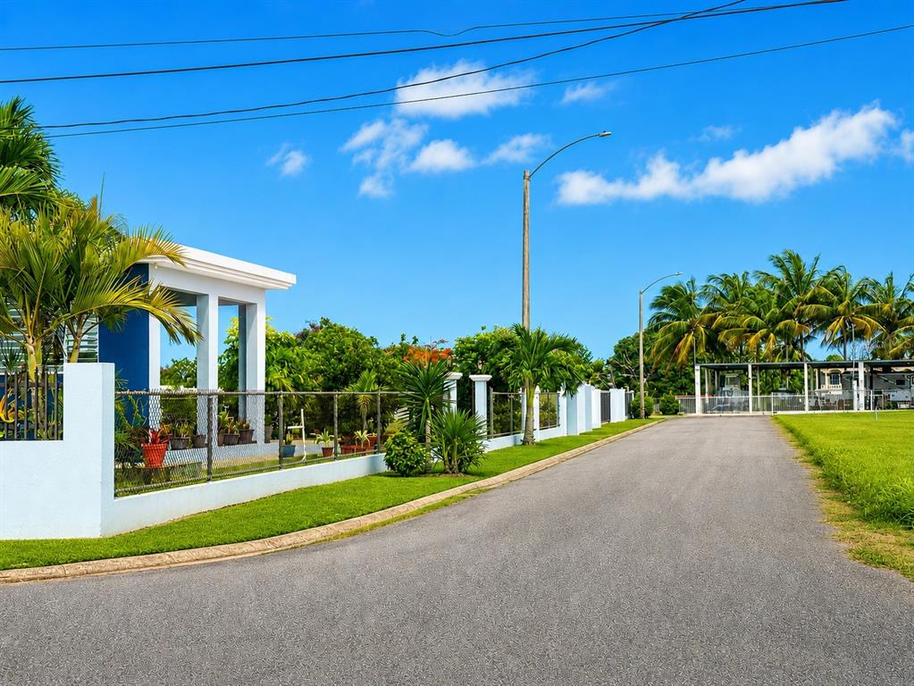 A paved road leads past a white-fenced property with palm trees and a blue structure — 467 BARRIO CAMASEYES, AGUADILLA, KM 4.8 INT, AGUADILLA, PR