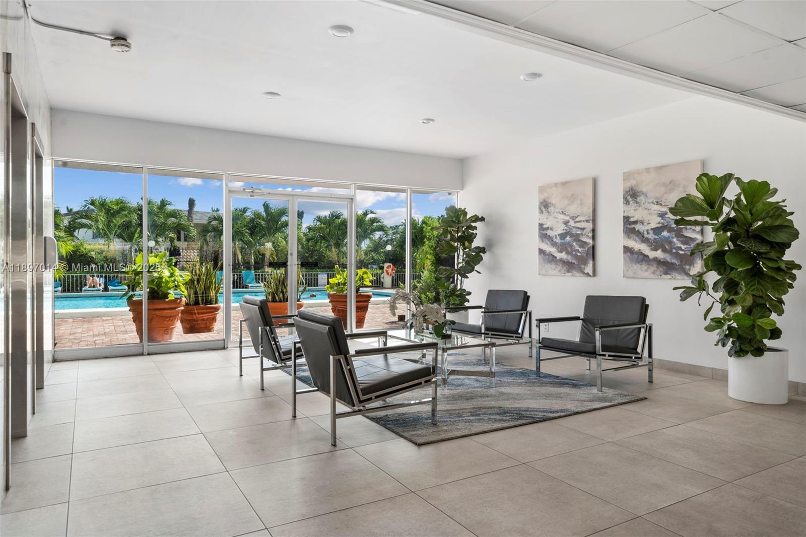 A modern lobby features four black leather chairs, a glass coffee table, and pool views — 401 Golden Isles Dr # 304, Hallandale Beach FL 33009, HALLANDALE BEACH, FL