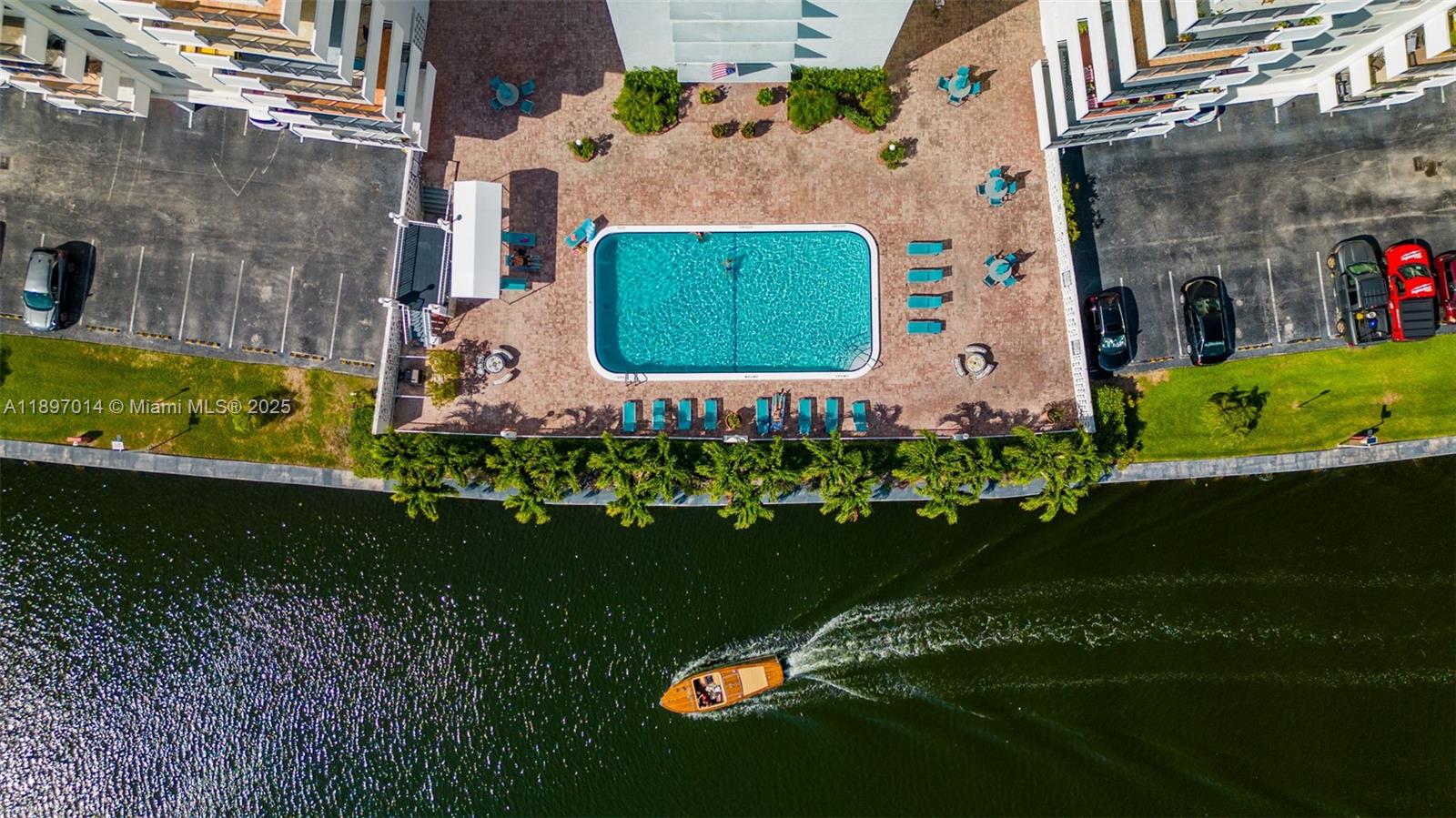 An aerial view shows a swimming pool, patio area, and a boat on the water — 401 Golden Isles Dr # 304, Hallandale Beach FL 33009, HALLANDALE BEACH, FL