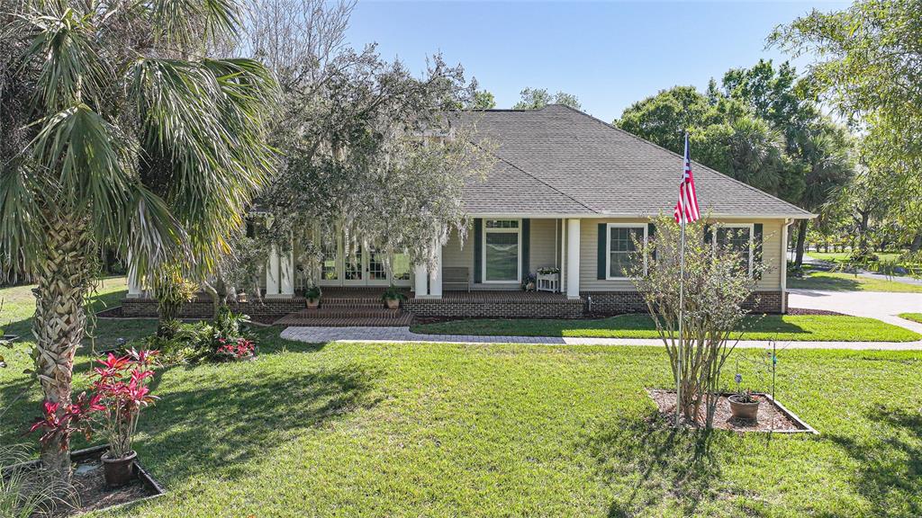 A single-story house with a brick porch, tan siding, and a large front lawn — 12222 SW AUSTIN AVENUE, LAKE SUZY, FL