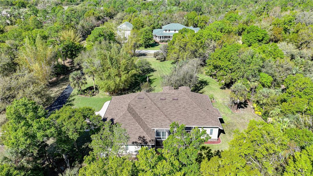 An aerial view shows a large house with a brown roof surrounded by dense trees — 12222 SW AUSTIN AVENUE, LAKE SUZY, FL