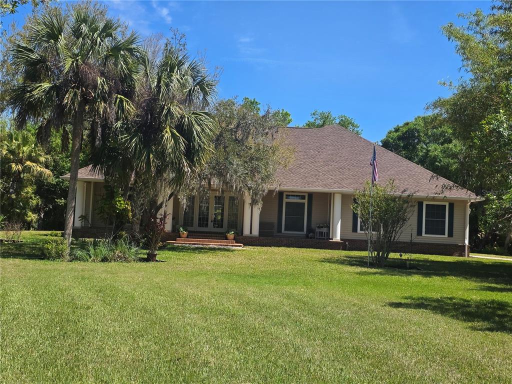 A single-story house with a brown roof, tan siding, and a front porch with columns — 12222 SW AUSTIN AVENUE, LAKE SUZY, FL