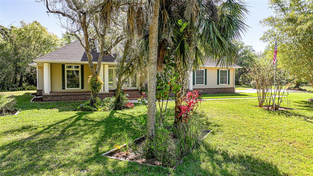 A single-story house with tan siding, a brick foundation, and a large front yard — 12222 SW AUSTIN AVENUE, LAKE SUZY, FL