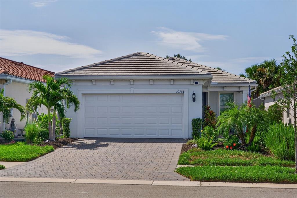 A single-story house with a white garage door, tiled roof, and a paved driveway — 10354 ABACO FALLS DRIVE, ENGLEWOOD, FL