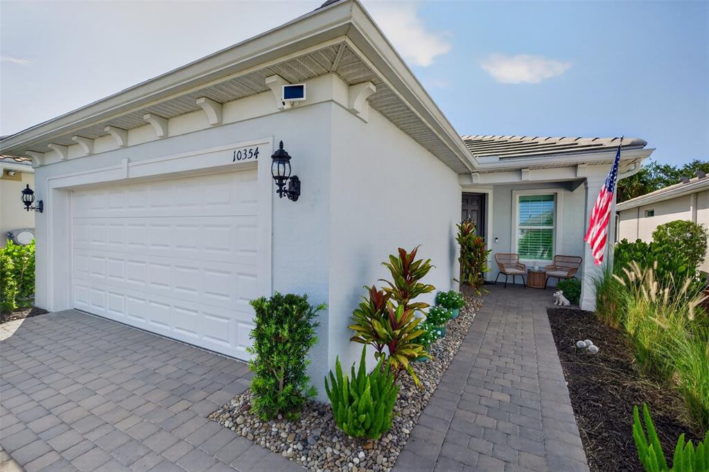 A single-story house exterior features a white stucco facade, a garage, and a paved walkway — 10354 ABACO FALLS DRIVE, ENGLEWOOD, FL
