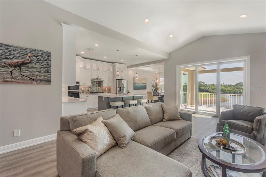 A living room with a gray sectional sofa opens to a kitchen and a waterfront view — 17B FRANKLIN COURT S, ST PETERSBURG, FL