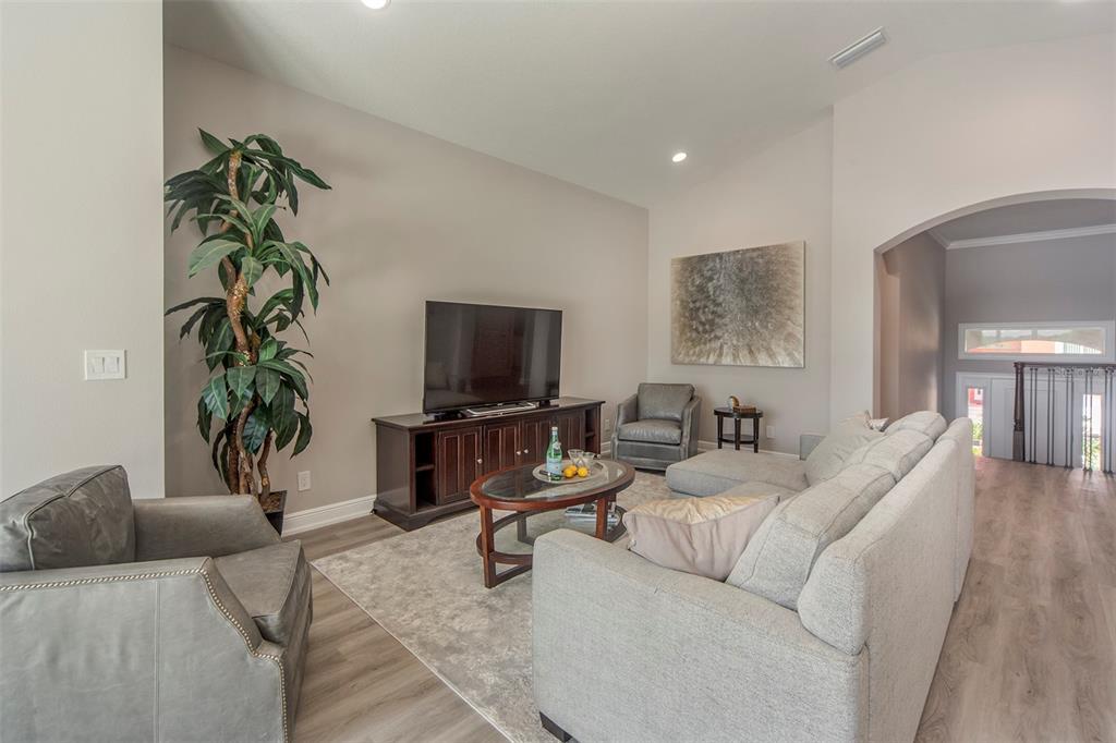A living room features a grey sectional, two armchairs, a television console, and wood flooring — 17B FRANKLIN COURT S, ST PETERSBURG, FL