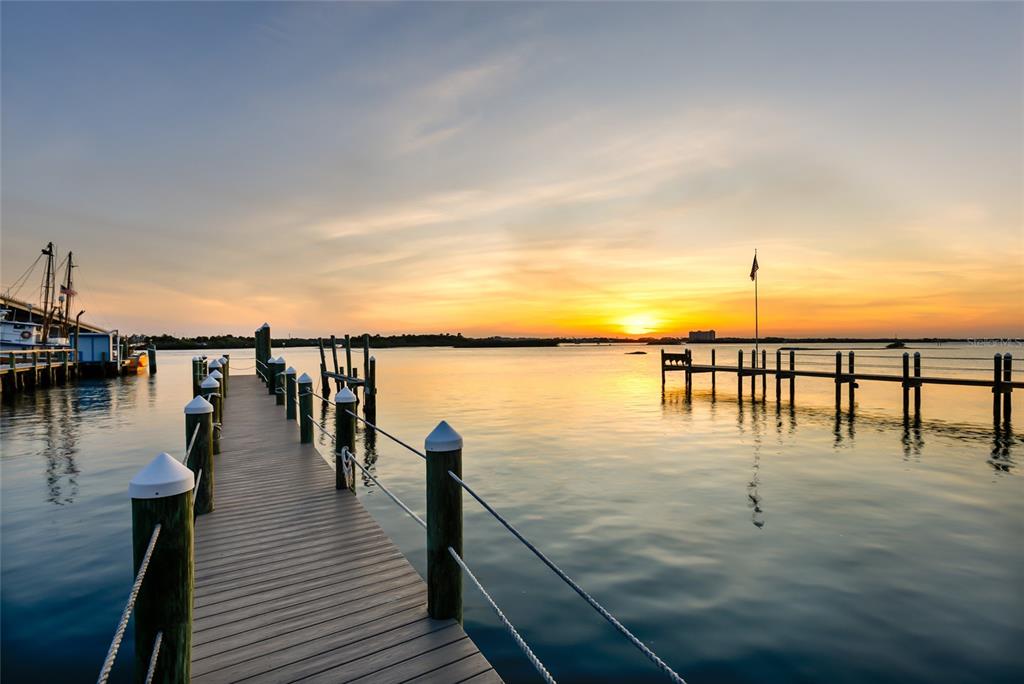A wooden dock extends into calm water toward a sunset horizon with distant land — 122 CORAL WAY, PORT ORANGE, FL