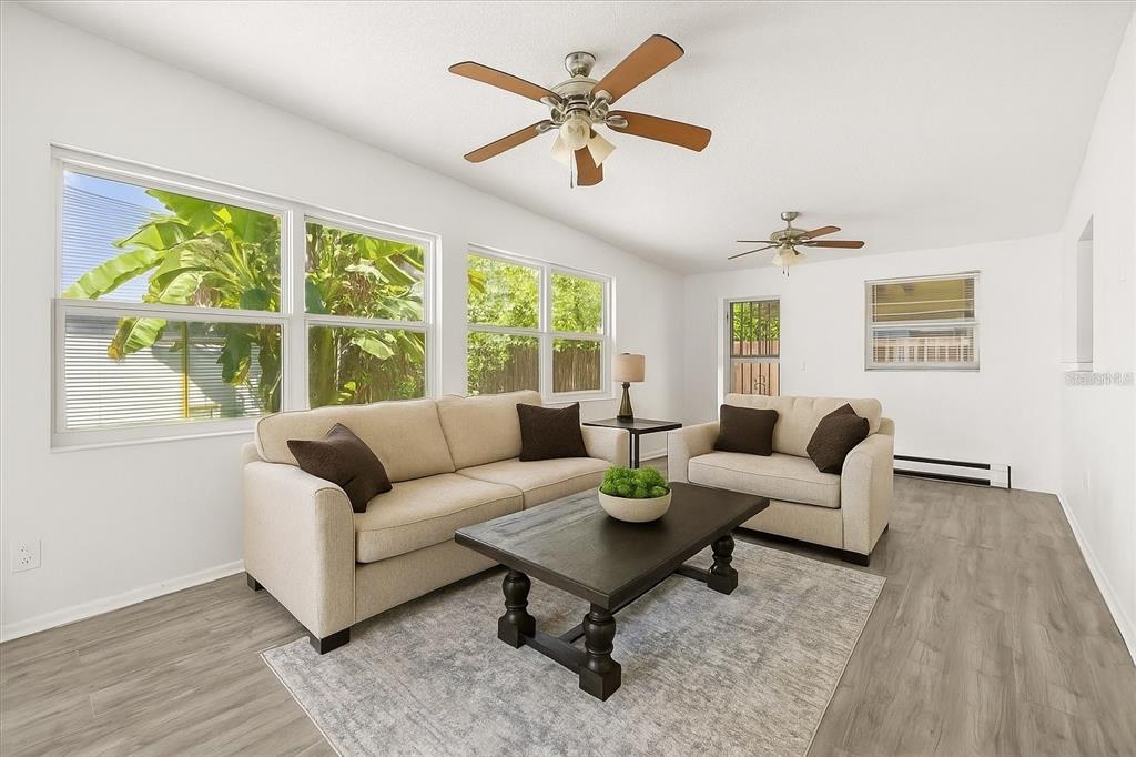 A living room with light-colored sofas, a dark wood coffee table, and two ceiling fans — 1849 VIBURNUM LANE, WINTER PARK, FL