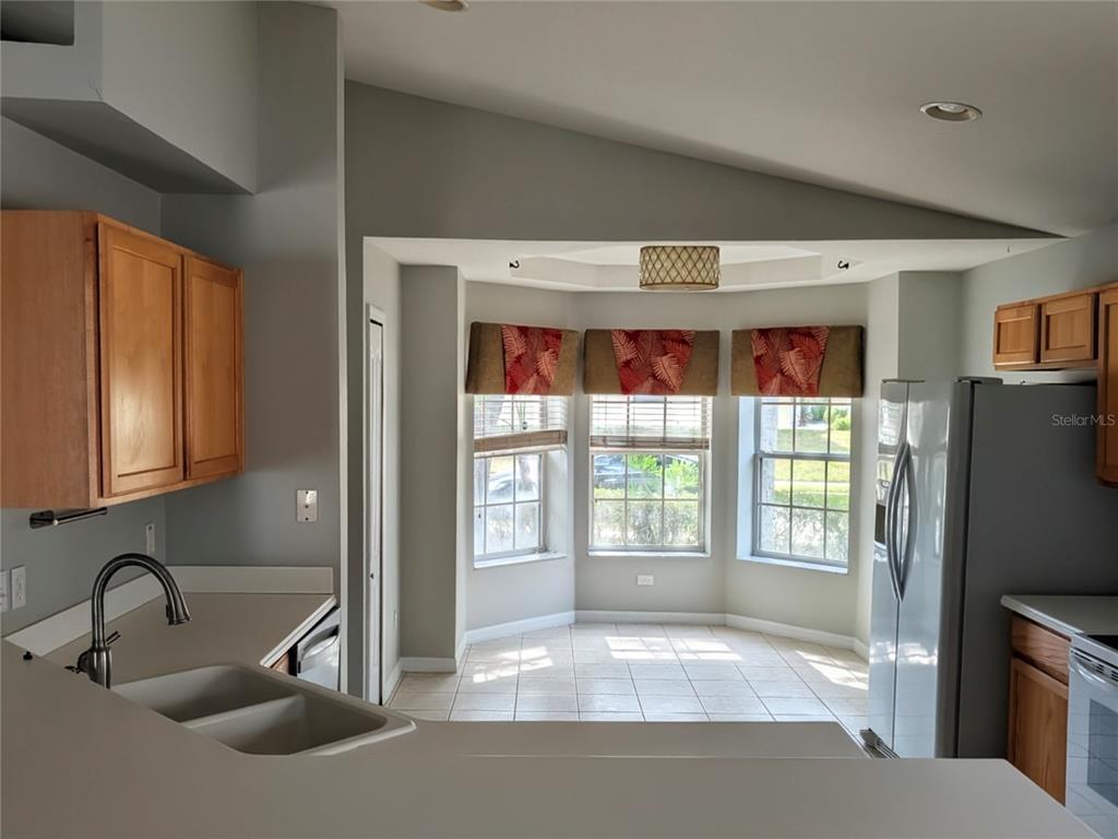 A kitchen features light wood cabinets, a double sink, and a breakfast nook with windows — 732 HENLEY CIRCLE, DAVENPORT, FL